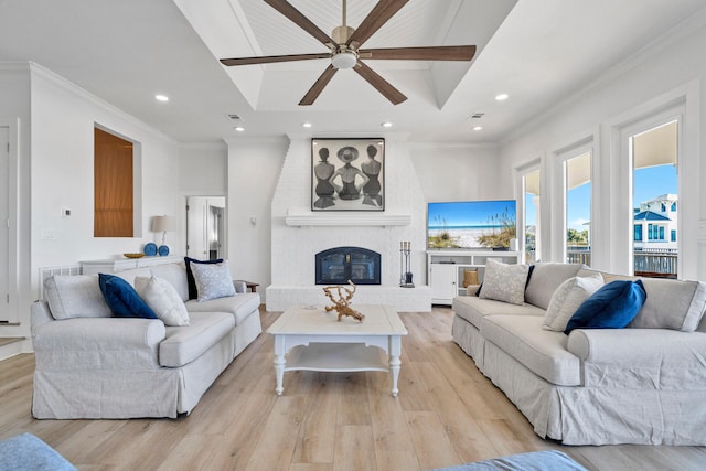 living room with a fireplace, ceiling fan, light wood-type flooring, and ornamental molding