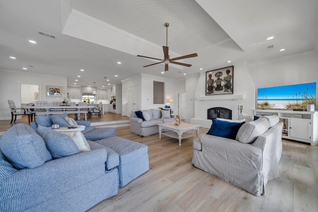 living room with light hardwood / wood-style flooring, a fireplace, ceiling fan, and crown molding