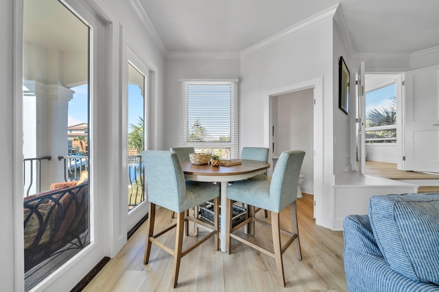 dining room with light hardwood / wood-style flooring, crown molding, and plenty of natural light