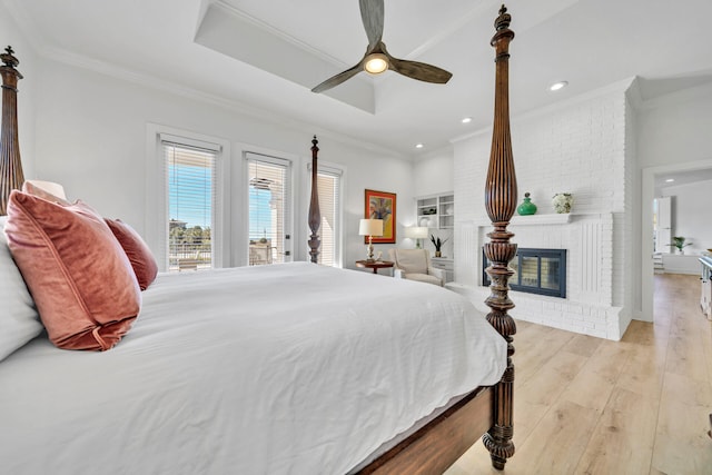 bedroom featuring access to outside, a fireplace, light wood-type flooring, crown molding, and ceiling fan