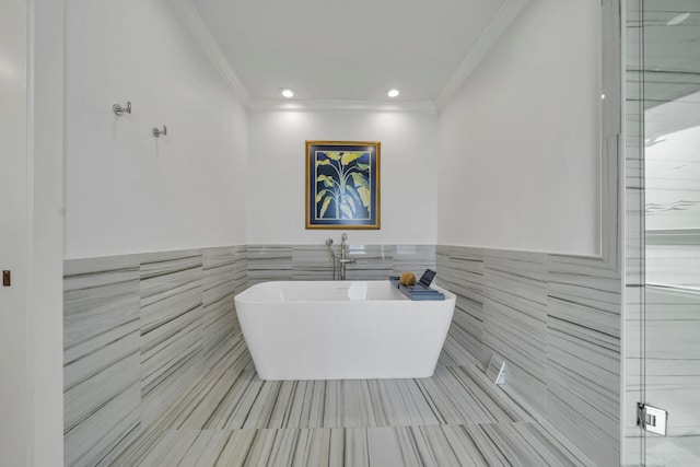 bathroom with tile walls, crown molding, tile floors, and a bath