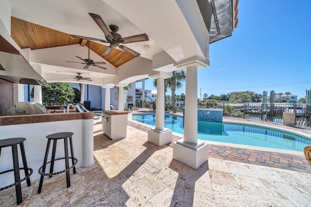 view of pool with a patio, exterior bar, ceiling fan, and an outdoor kitchen