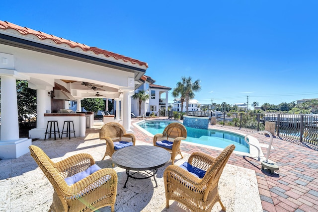 view of swimming pool with a patio, ceiling fan, and a bar