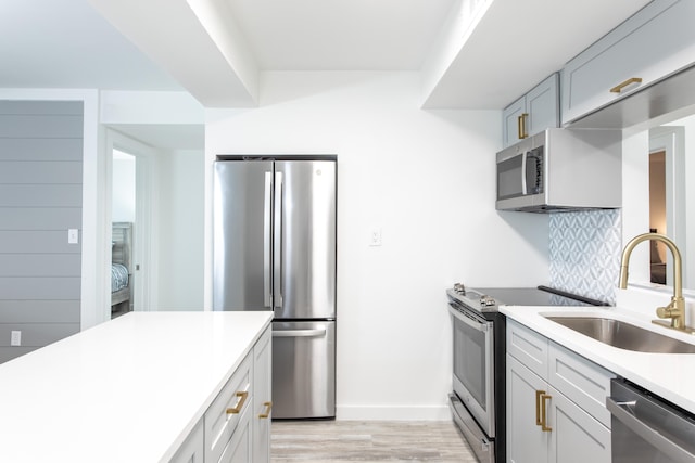 kitchen with light hardwood / wood-style floors, appliances with stainless steel finishes, tasteful backsplash, and sink