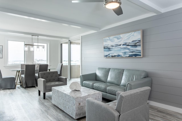 living room featuring light hardwood / wood-style flooring, ceiling fan, and beam ceiling