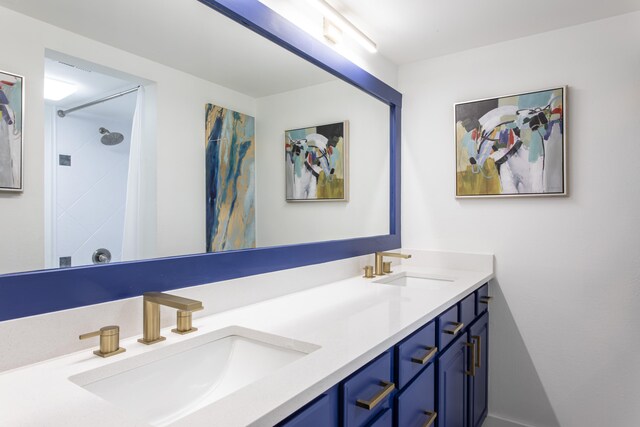 bathroom with dual bowl vanity and a tile shower