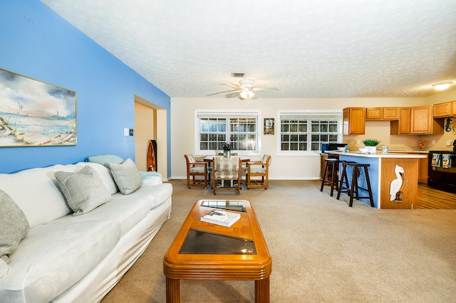 carpeted living room featuring a textured ceiling and ceiling fan