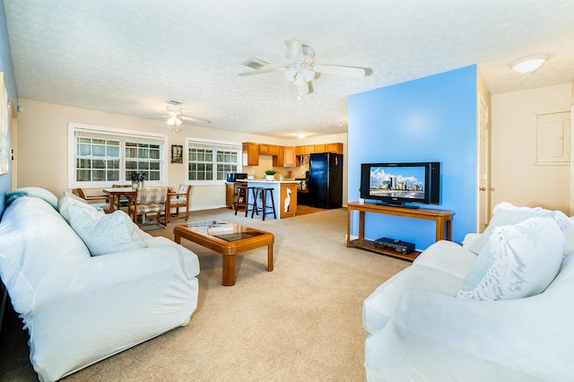 living room featuring ceiling fan, a textured ceiling, and light carpet