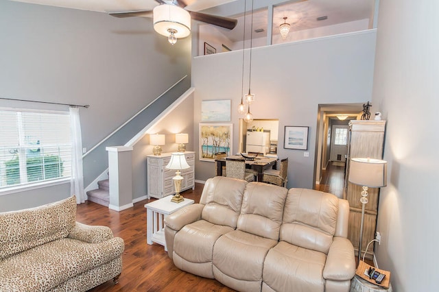 living room featuring ceiling fan, dark hardwood / wood-style flooring, and a towering ceiling