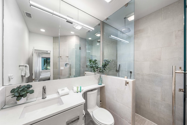 bathroom with a shower with door, toilet, tile walls, and large vanity