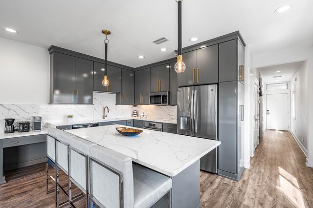 kitchen with wood-type flooring, pendant lighting, stainless steel appliances, and a center island