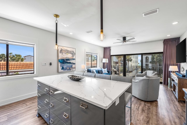 kitchen with a kitchen island, decorative light fixtures, ceiling fan, and hardwood / wood-style floors