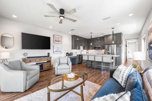 living room featuring ceiling fan, sink, and dark wood-type flooring