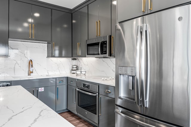 kitchen featuring gray cabinetry, stainless steel appliances, dark hardwood / wood-style floors, and light stone countertops