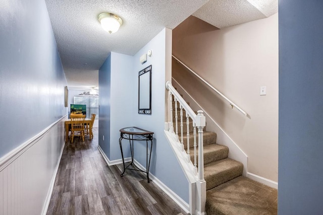 stairway featuring a textured ceiling and dark wood-type flooring