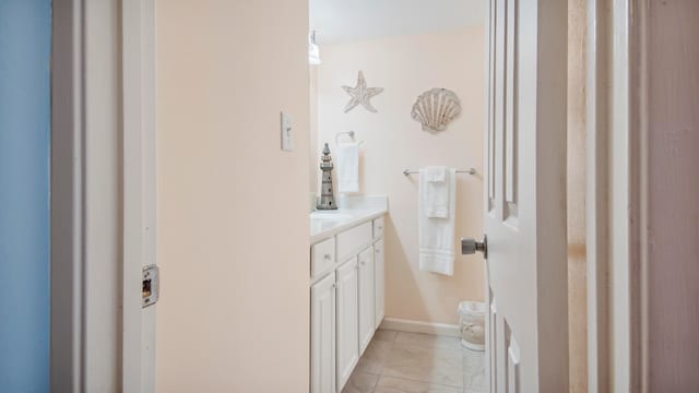 half bathroom featuring baseboards, vanity, toilet, and tile patterned floors