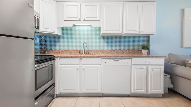 kitchen featuring stainless steel appliances, white cabinetry, a sink, and decorative backsplash