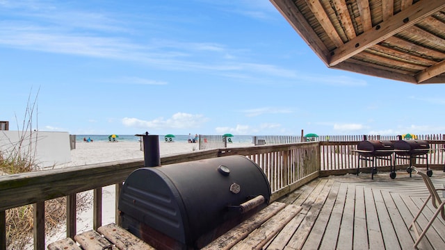 wooden terrace featuring a water view and a beach view