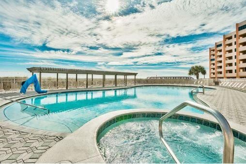 pool featuring a community hot tub and fence