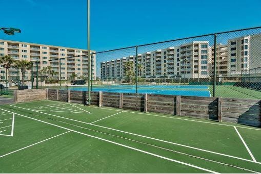 view of tennis court with a view of city, shuffleboard, and fence