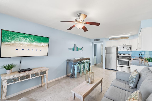 living area featuring visible vents, baseboards, ceiling fan, and light tile patterned flooring