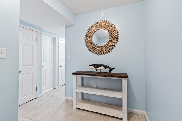 hallway featuring light tile patterned floors and baseboards