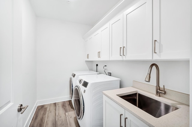 clothes washing area with separate washer and dryer, cabinets, light wood-type flooring, hookup for a washing machine, and sink