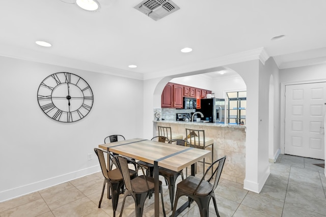 tiled dining area featuring sink and ornamental molding