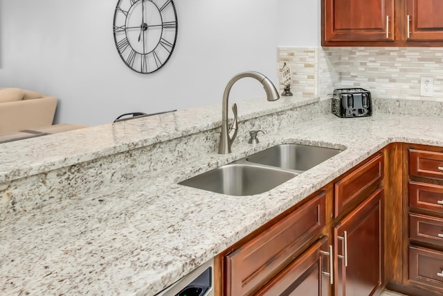 kitchen with backsplash, light stone countertops, and sink