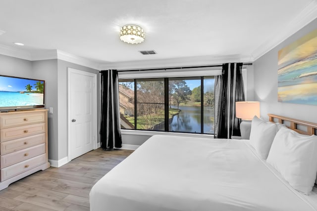 bedroom featuring a water view, light wood-type flooring, and ornamental molding