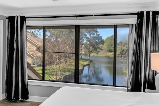 bedroom with hardwood / wood-style flooring, a water view, crown molding, and multiple windows