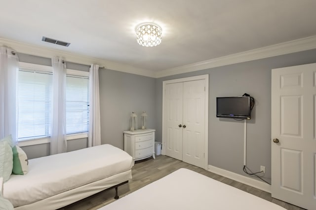 bedroom with a closet, ornamental molding, and hardwood / wood-style flooring