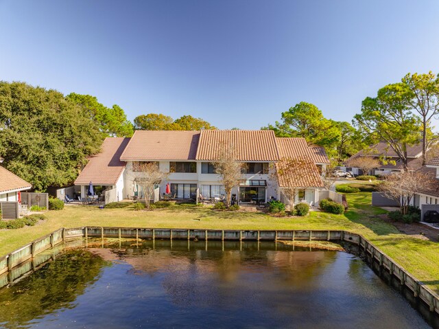 back of property featuring a yard, a water view, and a balcony