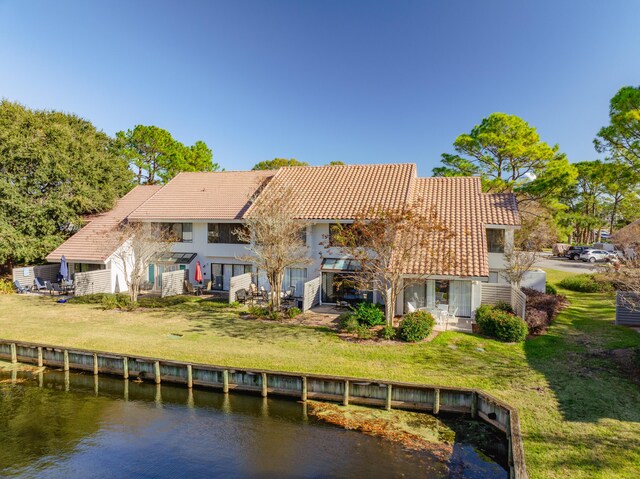 rear view of property featuring a water view and a lawn