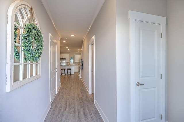 hall with ornamental molding and light hardwood / wood-style floors