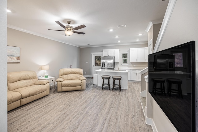 living room featuring light hardwood / wood-style floors, crown molding, sink, and ceiling fan