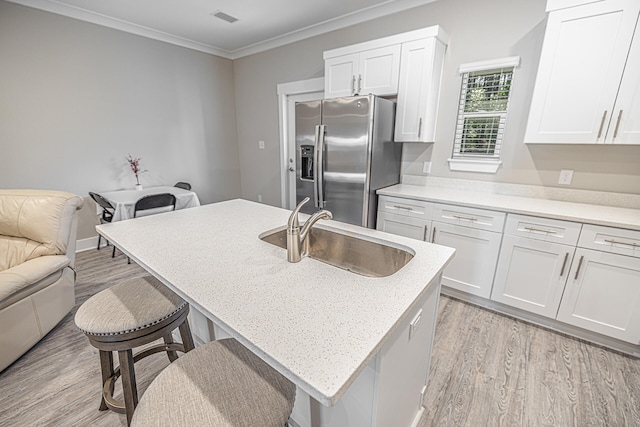 kitchen featuring light hardwood / wood-style flooring, a center island with sink, stainless steel refrigerator with ice dispenser, sink, and white cabinets