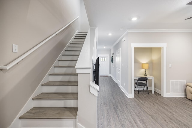 stairs with ornamental molding and hardwood / wood-style flooring