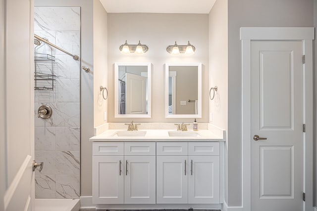 bathroom featuring dual bowl vanity and tiled shower