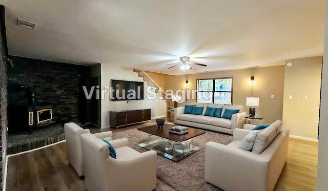 living room with a wood stove, hardwood / wood-style floors, and ceiling fan