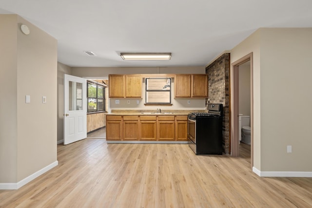 kitchen featuring sink, gas range, and light hardwood / wood-style floors