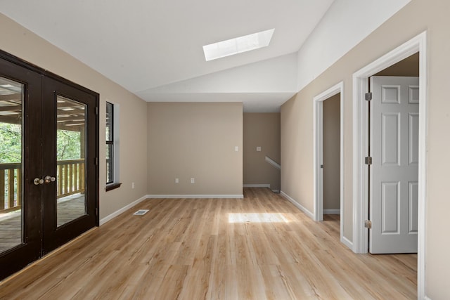 spare room featuring lofted ceiling with skylight, french doors, and light wood-type flooring