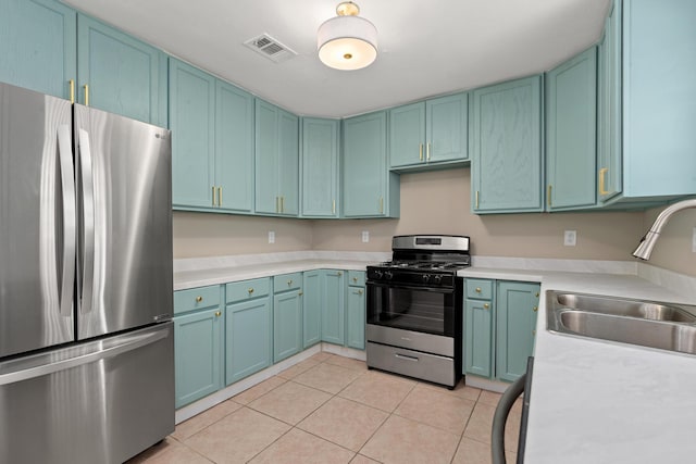 kitchen with sink, light tile patterned floors, stainless steel fridge, and gas stove