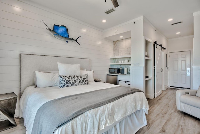 bedroom with fridge, crown molding, a barn door, light hardwood / wood-style floors, and ceiling fan