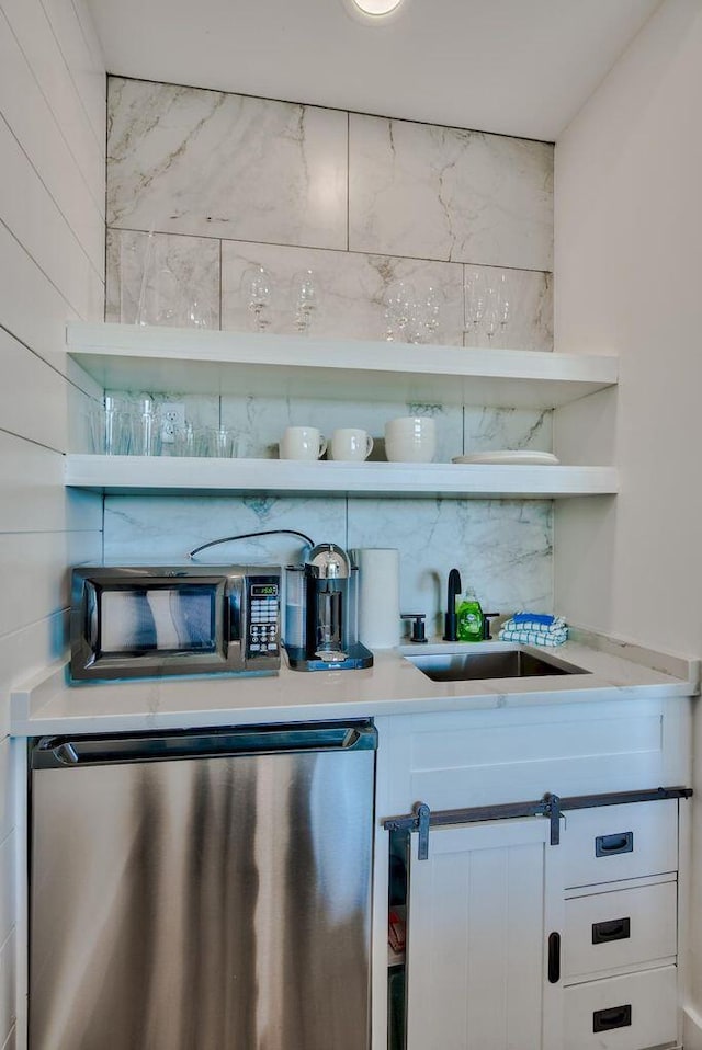 bar featuring white cabinets, sink, refrigerator, and backsplash