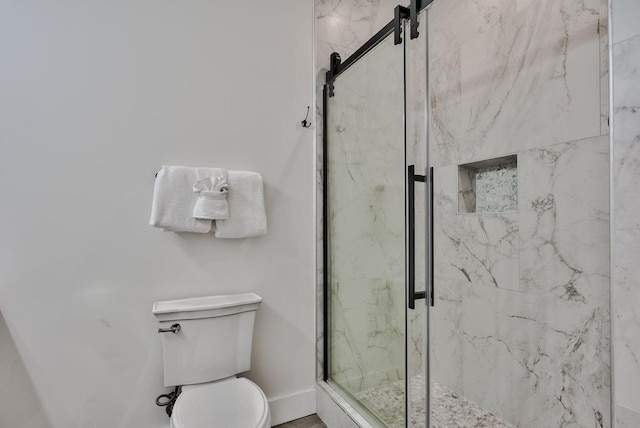 bathroom featuring a shower with door and toilet