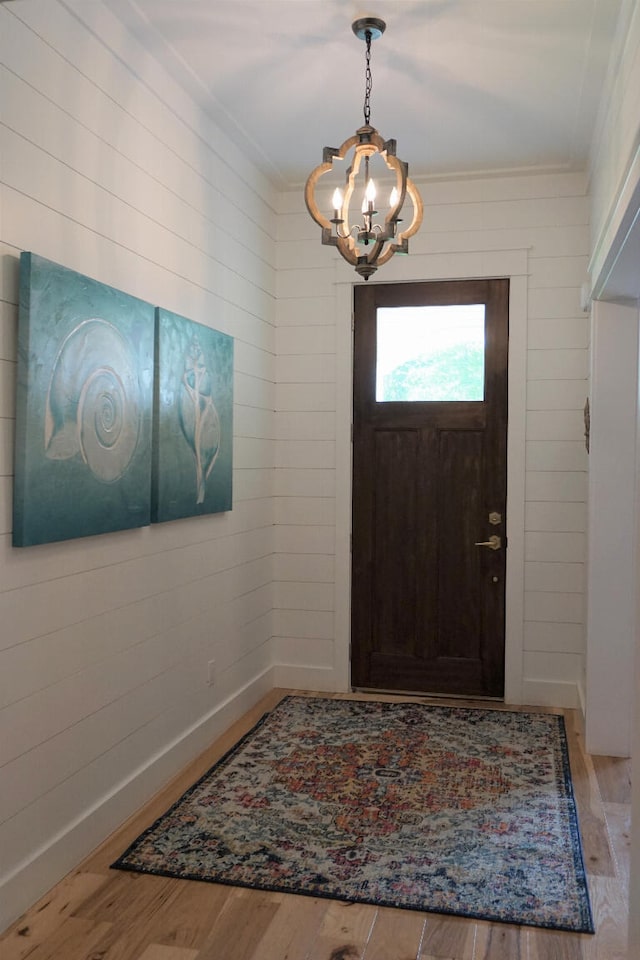 foyer entrance with crown molding, wood-type flooring, and a notable chandelier