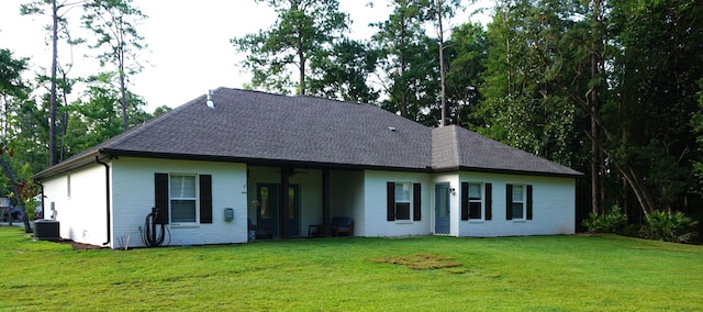 view of front of home featuring brick siding, a front yard, cooling unit, and a shingled roof