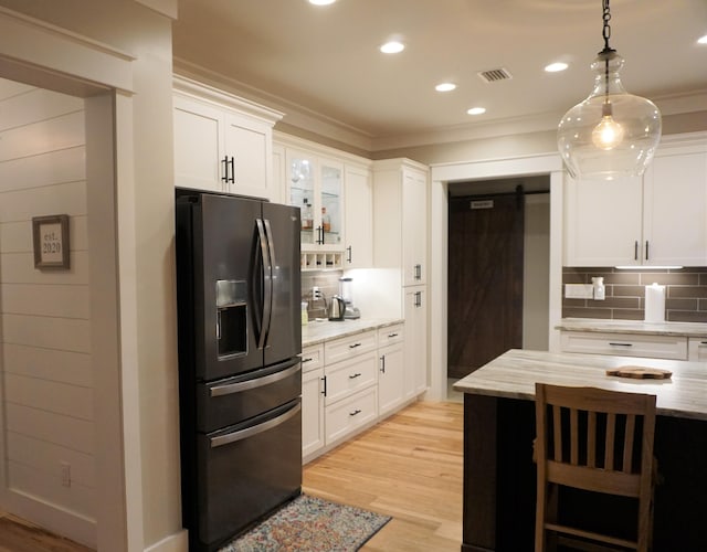 kitchen with hanging light fixtures, glass insert cabinets, black fridge with ice dispenser, and white cabinetry