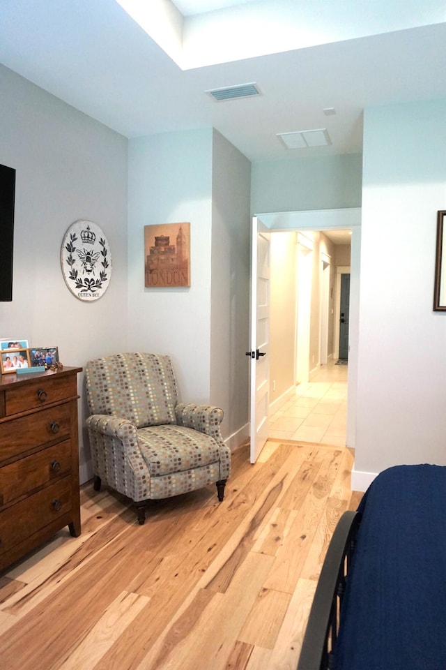 bedroom with baseboards, visible vents, and light wood finished floors